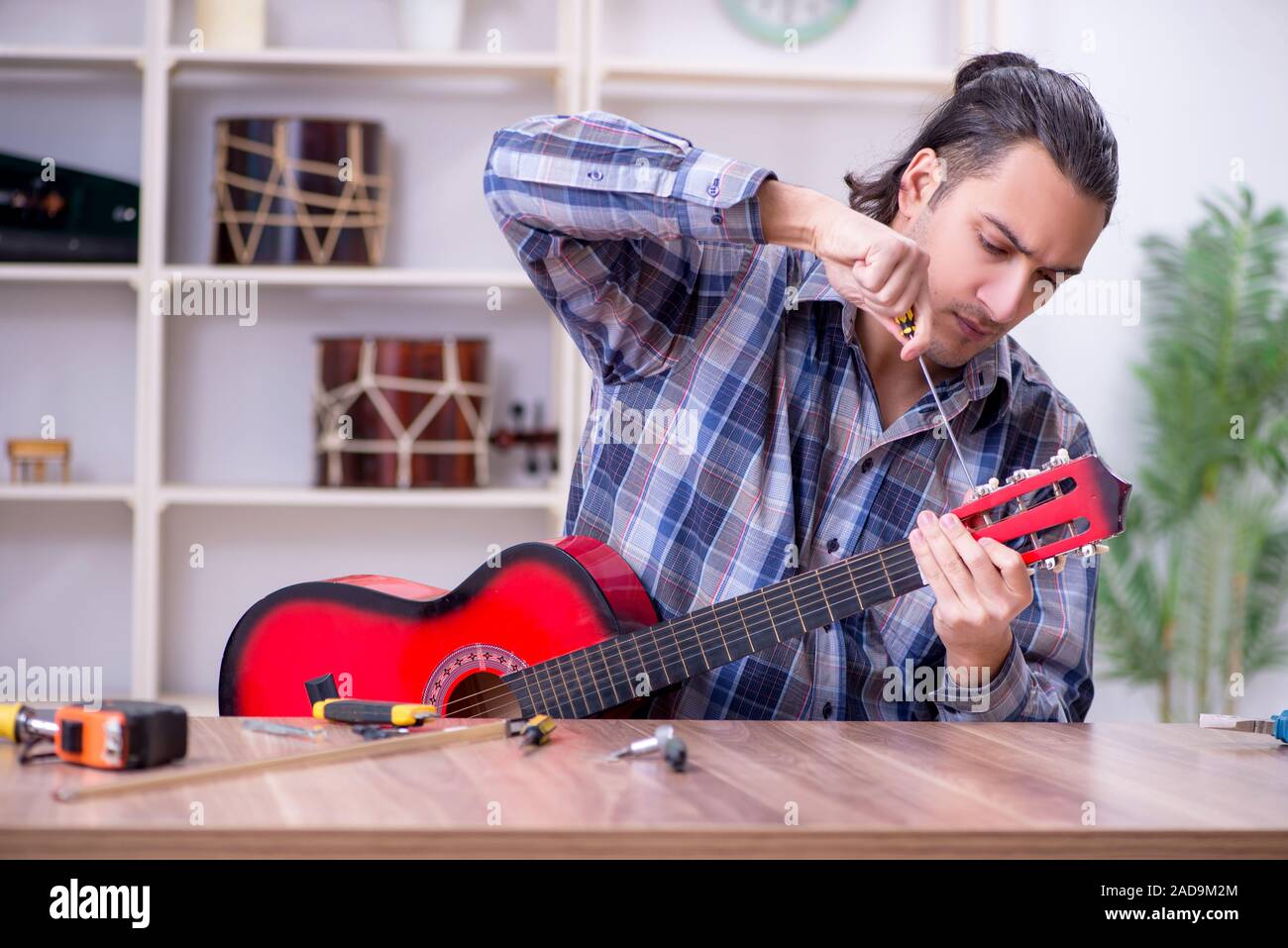 Junge schöne Handwerker Reparatur Gitarre Stockfoto