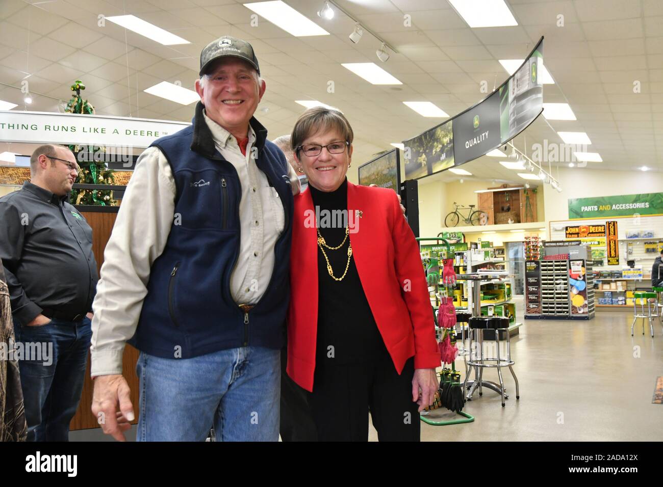 Emporia, Kansas, USA, 3. Dezember 2019 Gouverneur von Kansas Laura Kelly posiert für ein Foto mit Warren Schmidt Leiter Vertrieb für PrairieLand Partner der örtlichen John Deere Händler während einer Tour von der ho als Teil eines landesweiten Besuch in lokale Geschäfte Stockfoto