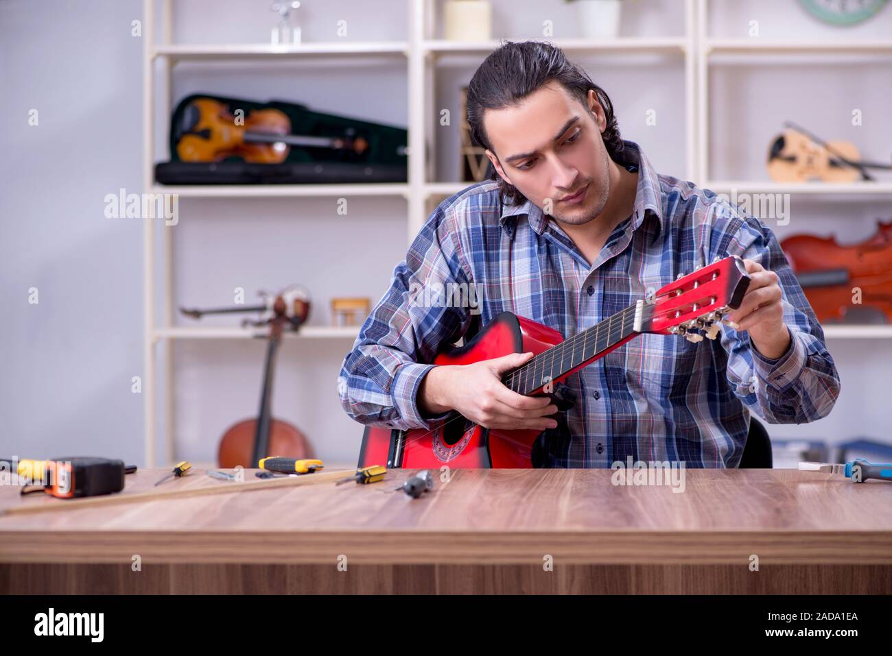 Junge schöne Handwerker Reparatur Gitarre Stockfoto