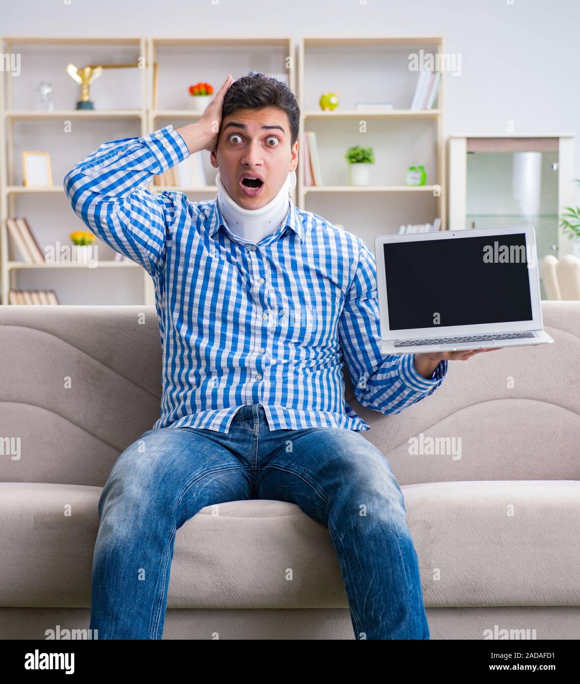 Mann Freiberufler in einer zervikalen Kragen Neck Brace von zu Hause aus arbeiten Stockfoto