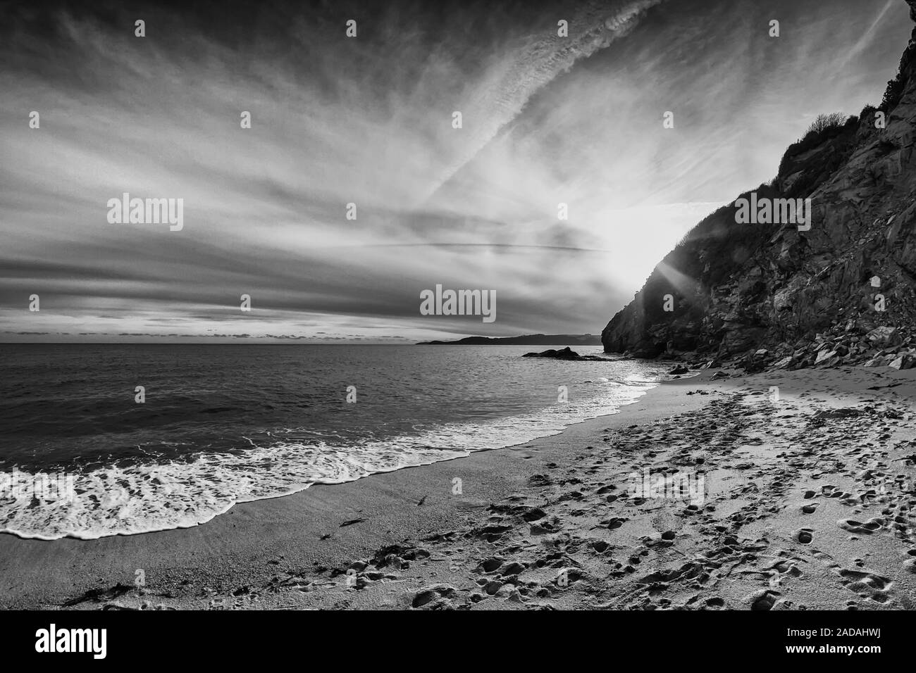 Die Sonne schön hinter den Klippen von St. Austell, Cornwall, England. Die Leute haben bereits den Strand verlassen. Stockfoto