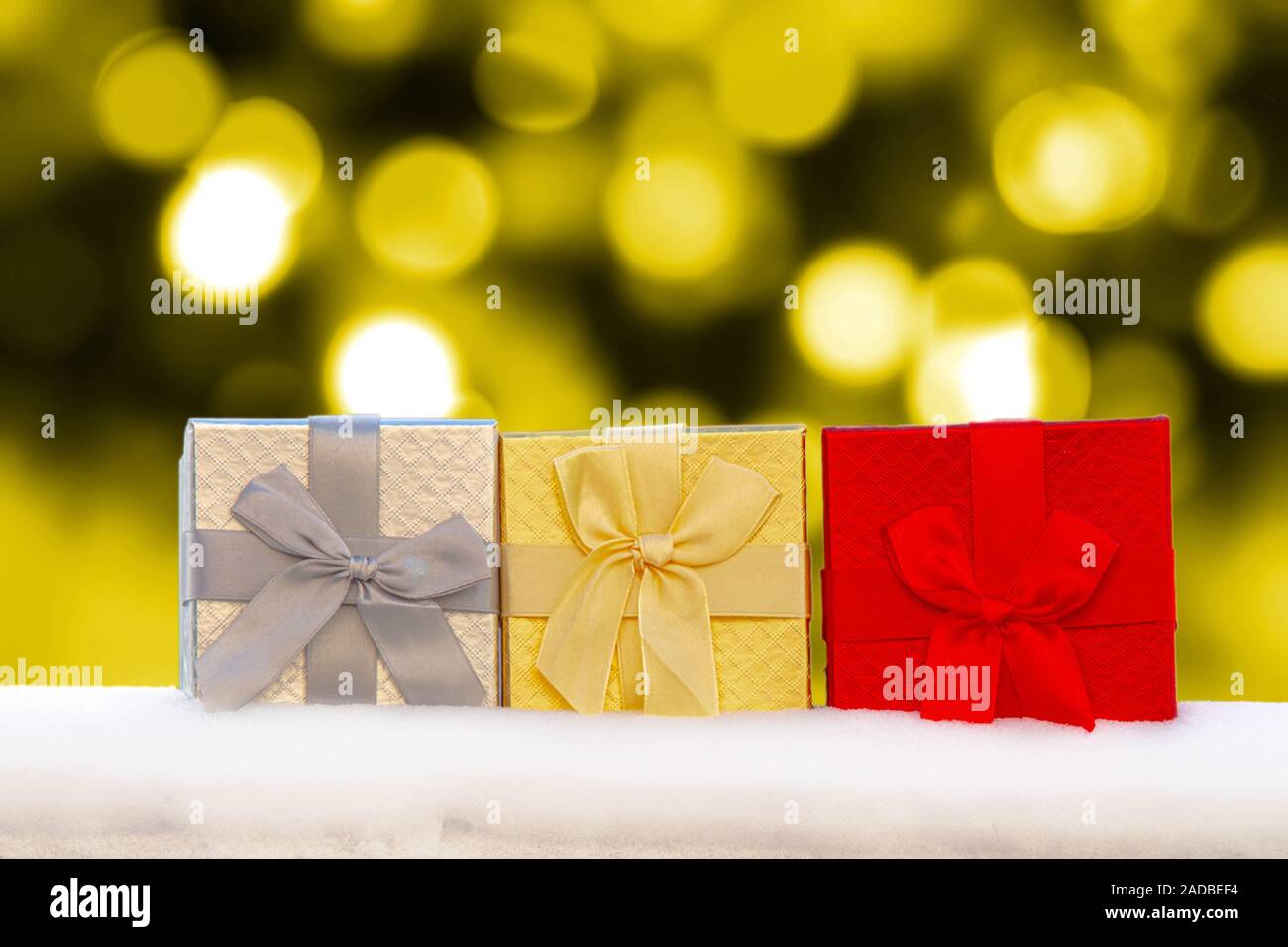 Bunte Gif Boxen präsentiert auf Schnee mit Golden christmas lights auf dem Hintergrund Stockfoto