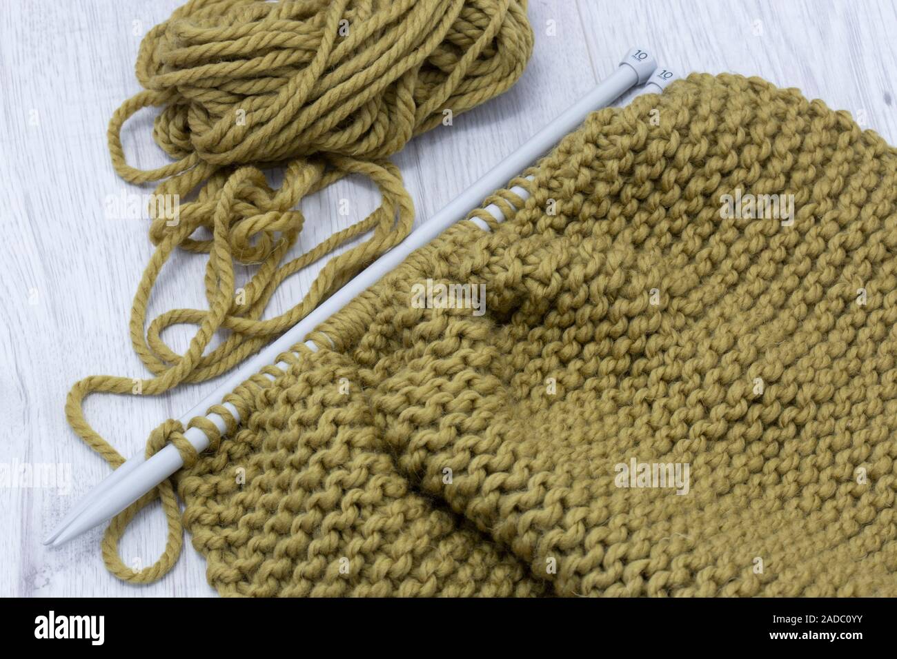 Stricken Pullover mit Merino Wolle Garn und mit einem Stricken nähen. Auf einem grauen Holz Oberfläche Stockfoto