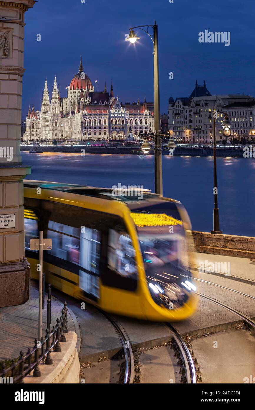 Budapest, Ungarn - Gelbe tram unterwegs an der Clark Adam Square mit beleuchteten Parlamentsgebäude im Hintergrund an der blauen Stunde Stockfoto
