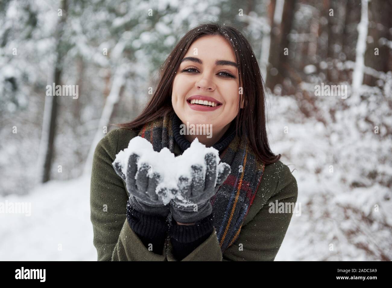 Happy brunette halten Schnee in der Hand und lächelt. Winter Forest Stockfoto