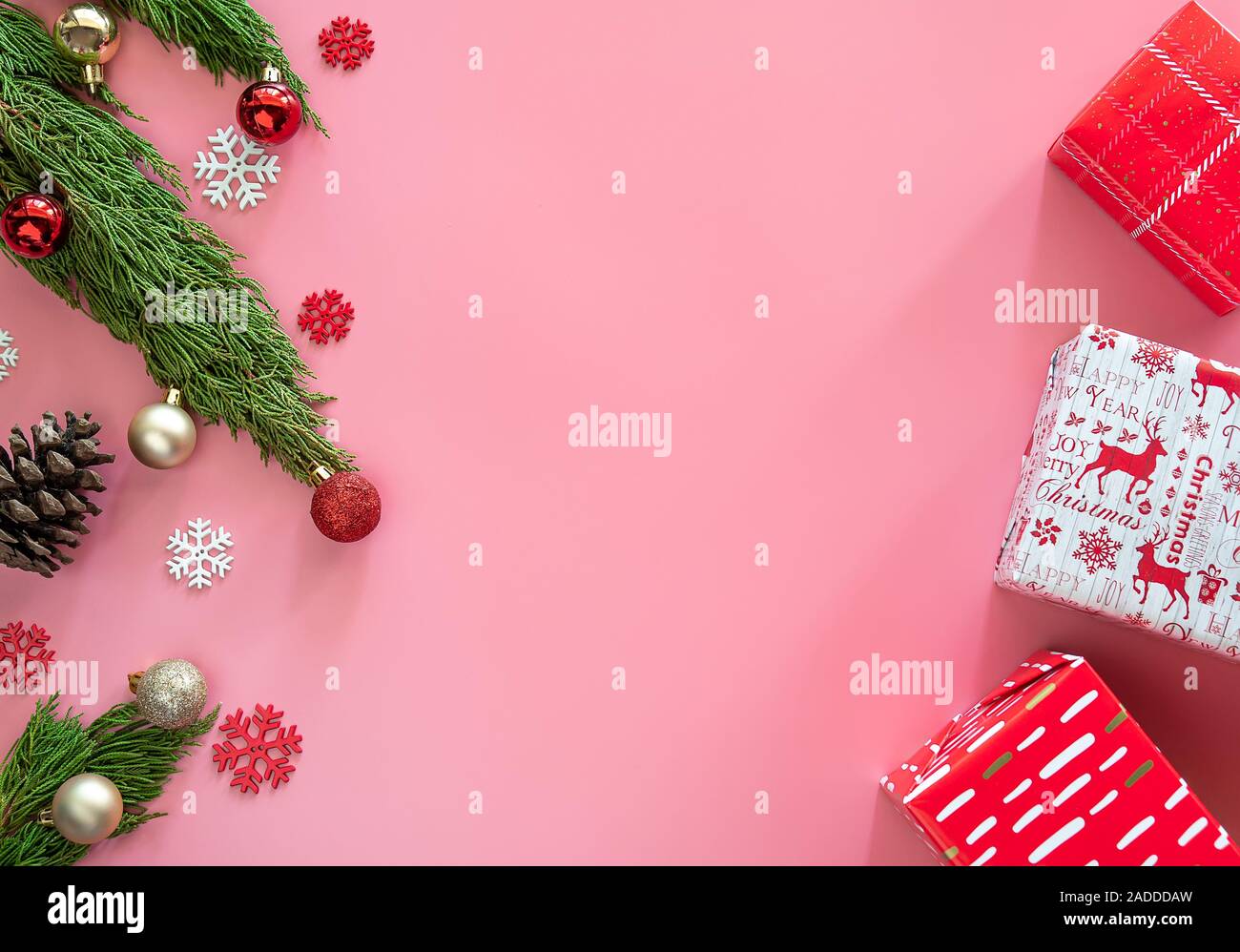 Green Pine, Pine Cone, Schneeflocken, Weihnachtsschmuck und Geschenkverpackung Geschenkpapier in Rot auf rosa Hintergrund mit Kopie Raum Stockfoto