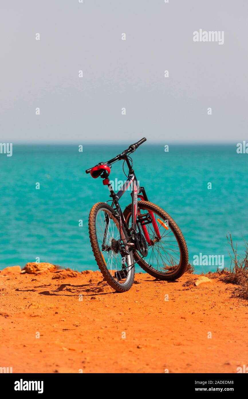 Fahrrad stehen am Ende eines roten Feldweg führt zum Indischen Ozean, Broome, West Kimberley, Western Australia Stockfoto