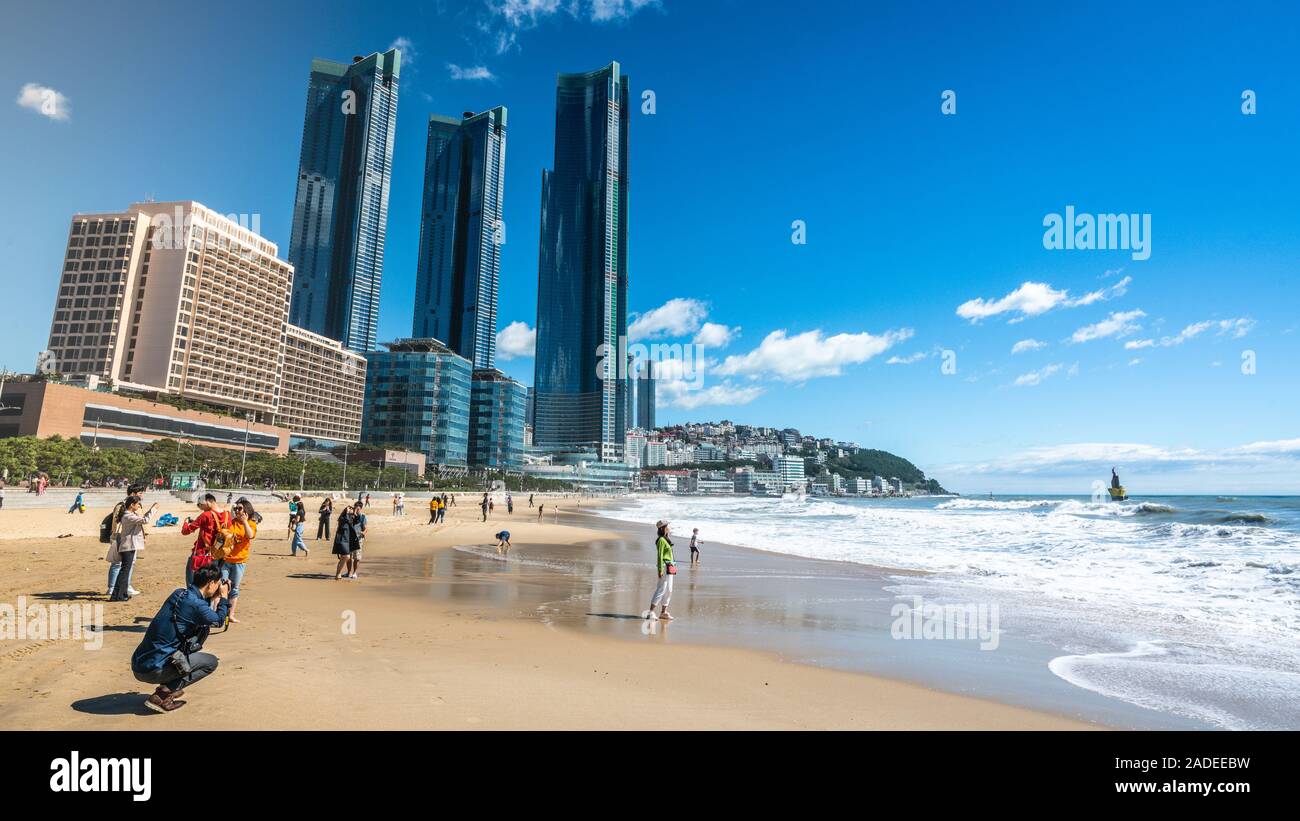 Busan, Korea, 3. Oktober 2019: asiatische Touristen auf Haeundae Beach an sonnigen Herbsttag und moderne Stadt Wolkenkratzer von Haeundae LCT Die scharfen im Hintergrund Stockfoto