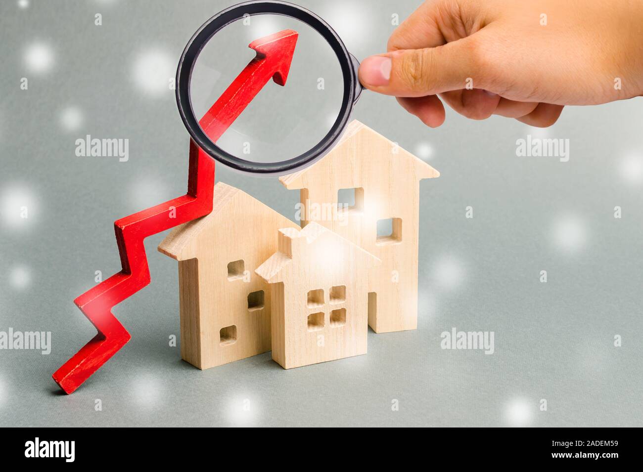 Miniatur Holzhäuser und Pfeil nach oben mit Schneeflocken. Das Konzept der hohen Gehäuse. Investitionen für Immobilien im Winter. Hypothek Zinsen Stockfoto