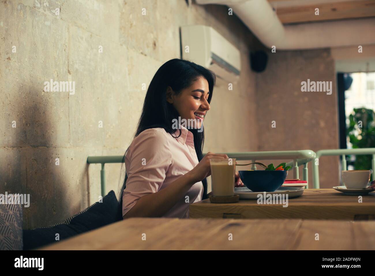Glückliche Frau essen leckere Salat und lächelnd Stockfoto