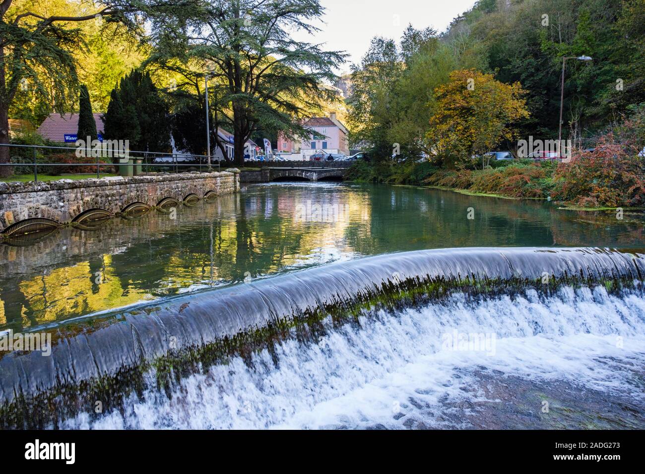 Die Mühle Teich mit Wasser fließt über einen der Dämme auf Cheddar Yeo Fluss durch das Dorf von Cheddar, Mendip, Somerset, England, Großbritannien, Großbritannien Stockfoto