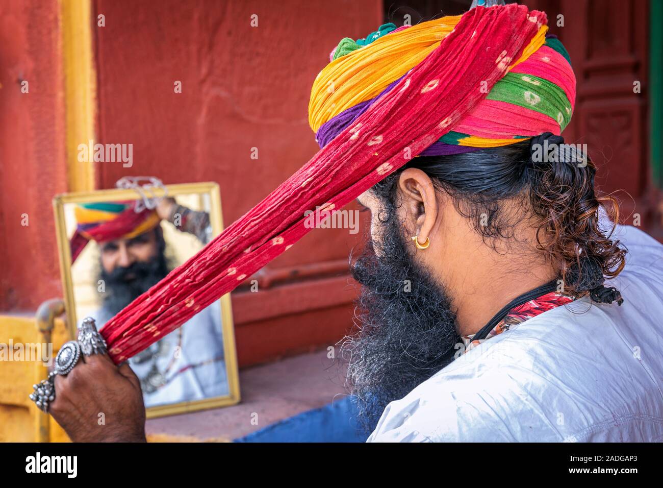 Mann bin auf seine Reflexion in einem Spiegel, wenn Binden seinen Turban, Jodhpur, Rajasthan, Indien Stockfoto