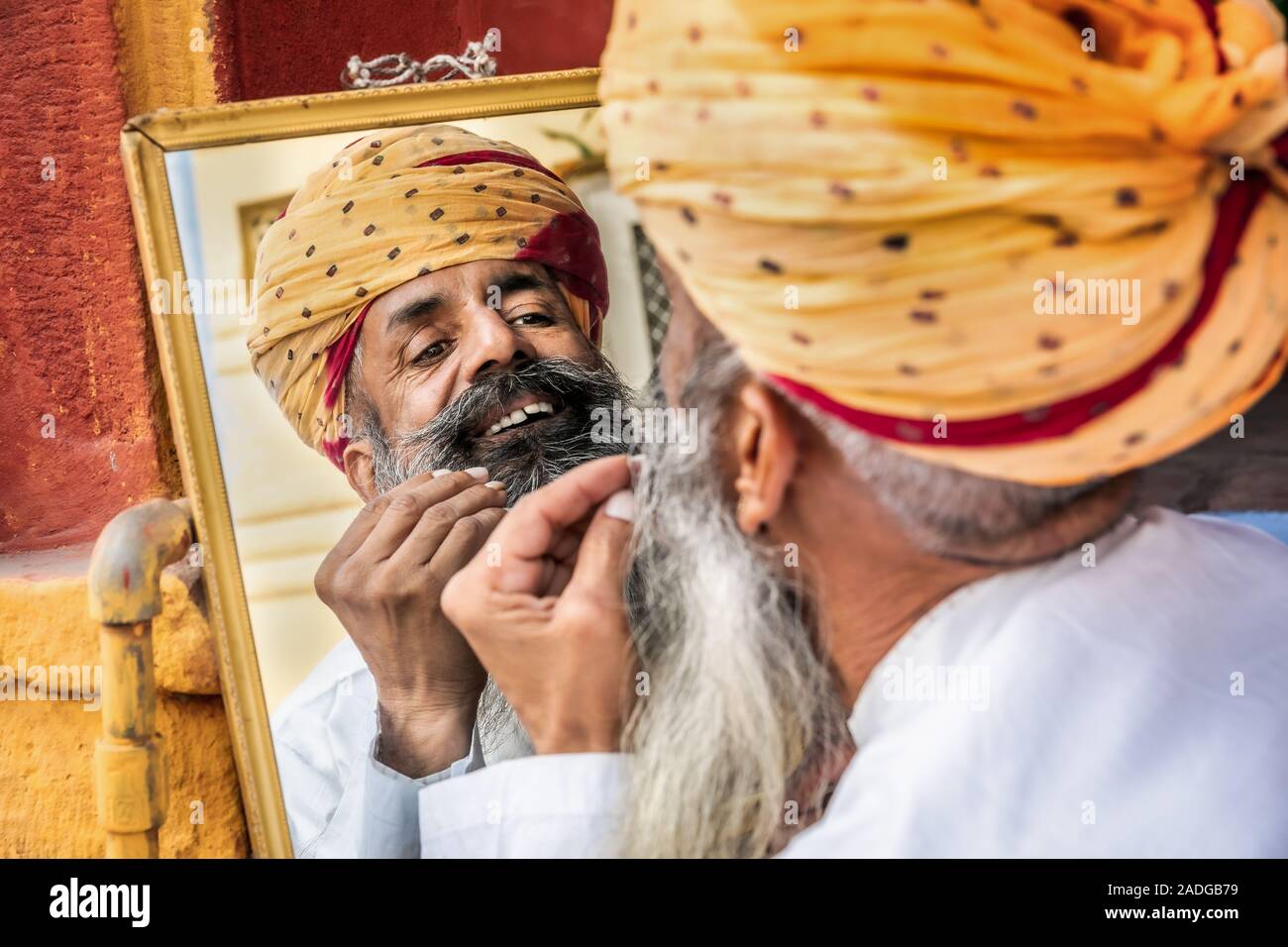 Mann bin auf seine Reflexion in einem Spiegel, wenn seinen Bart zur Festsetzung, Jodhpur, Rajasthan, Indien Stockfoto
