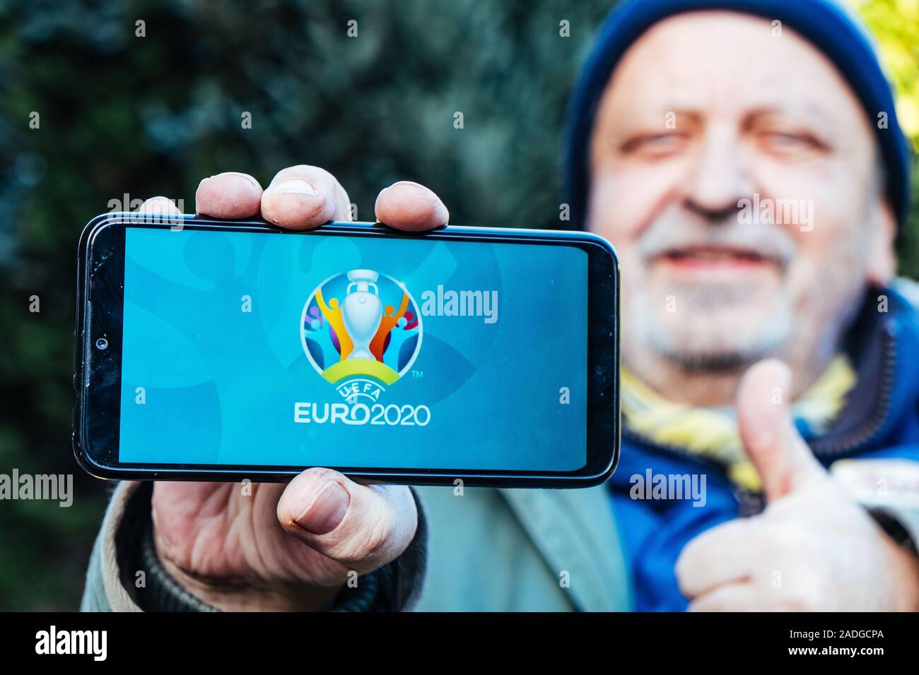 Älterer Mann hält ein Smartphone mit Logo der UEFA Euro 2020 auf dem Bildschirm Stockfoto