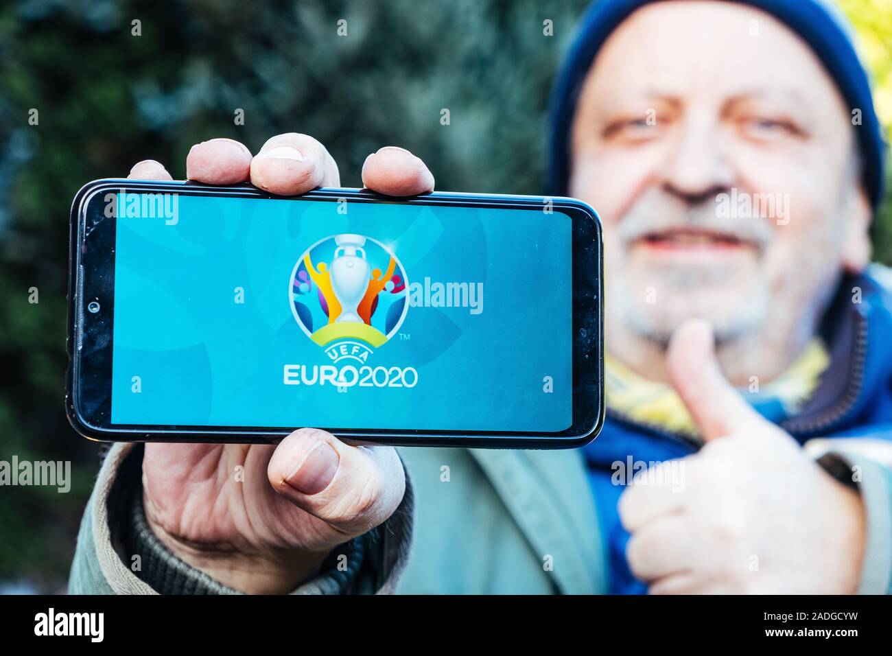 Älterer Mann hält ein Smartphone mit Logo der UEFA Euro 2020 auf dem Bildschirm Stockfoto
