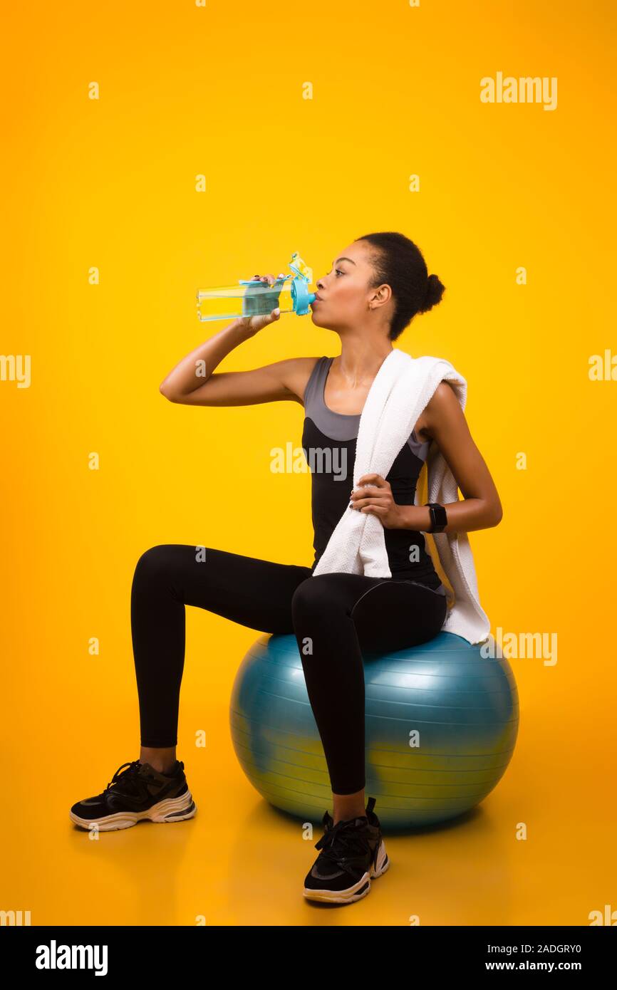 Arfo Fitness Mädchen sitzen auf fitball Trinkwasser, Studio Shot Stockfoto