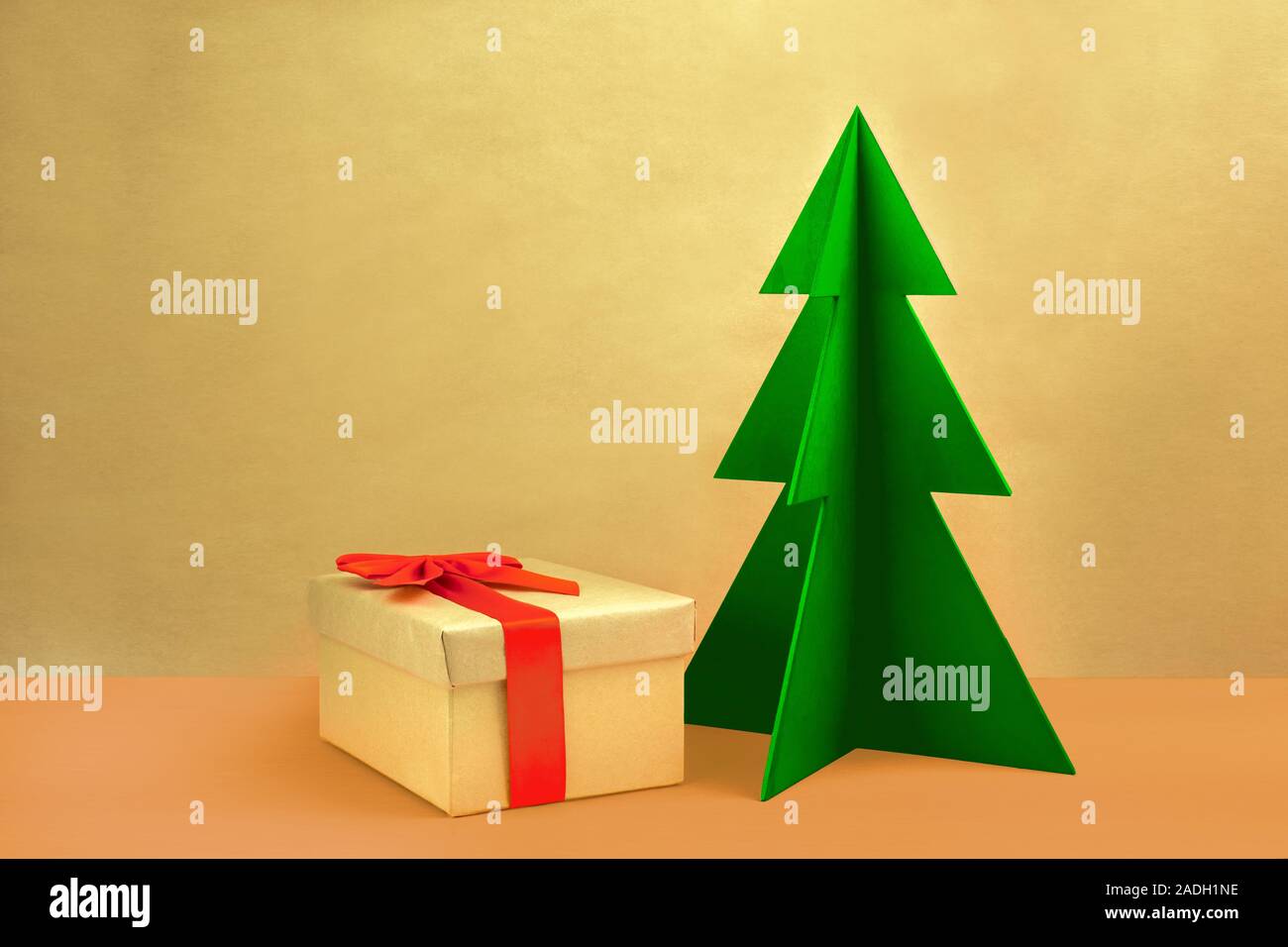 Geschenkbox mit roter Schleife und grünen Holz Weihnachtsbaum auf einem natürlichen braunen Hintergrund. Stockfoto