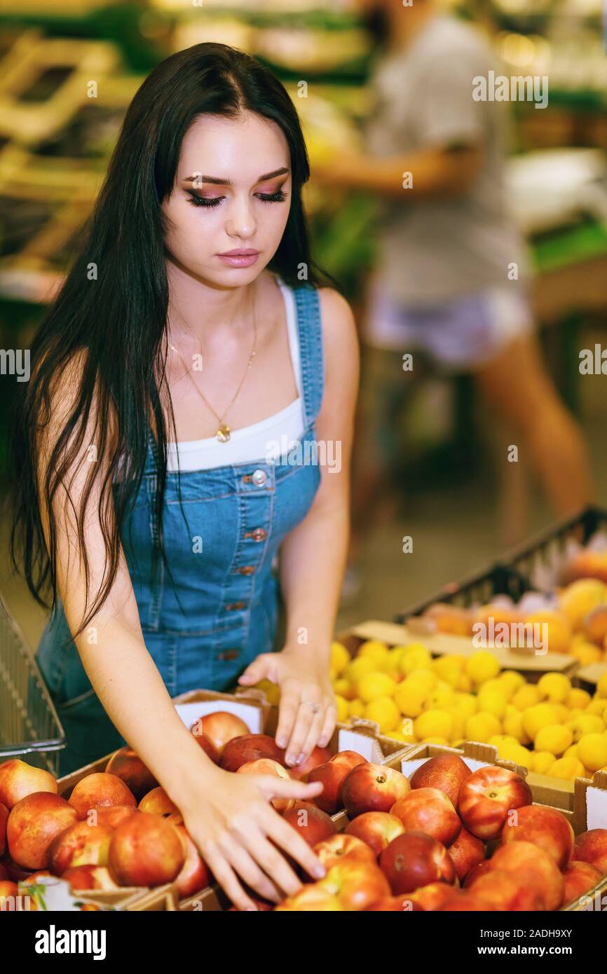 Junge Mädchen entscheidet sich für Pfirsiche in einem Supermarkt Stockfoto