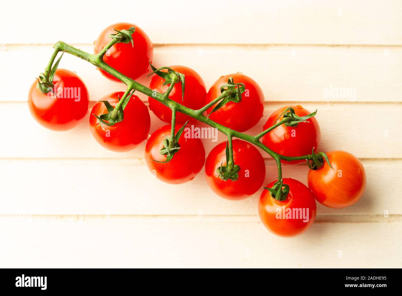 Grün Zweig der rote Kirschtomaten auf der Holzoberfläche Stockfoto