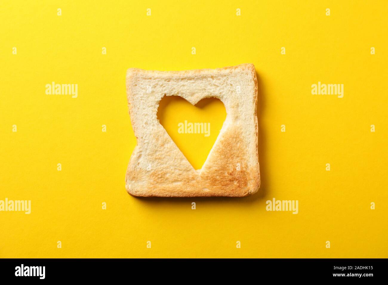 Toast Brot mit der Form des Herzens auf gelbem Hintergrund, Ansicht von oben Stockfoto