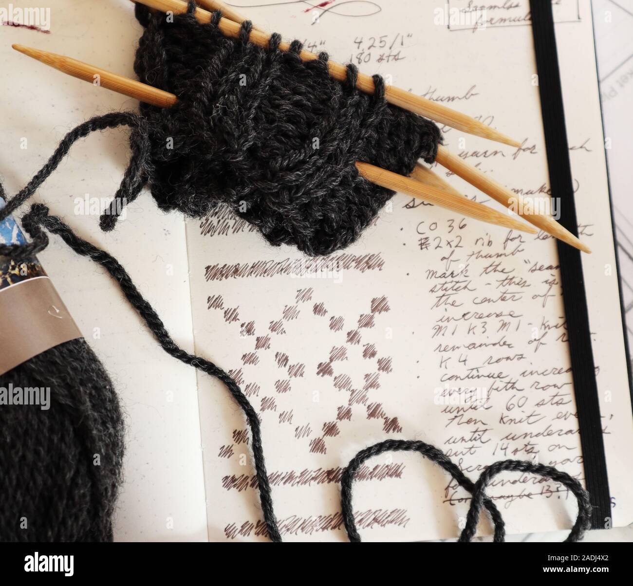 Handknit teilweise fertigen Pullover und die handschriftliche Muster mit Colorwork graph. Bamboo doppelseitige Stricknadeln und Holzkohle Garn Stockfoto