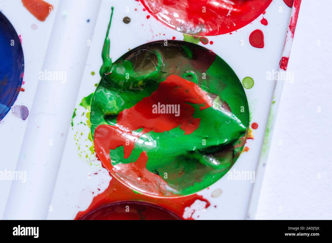 Ein Fleck mit roter Farbe in eine grüne Farbe. Eine Palette von Farben. Moderne Kunst Malen spritzen. Bunte curl. Stockfoto
