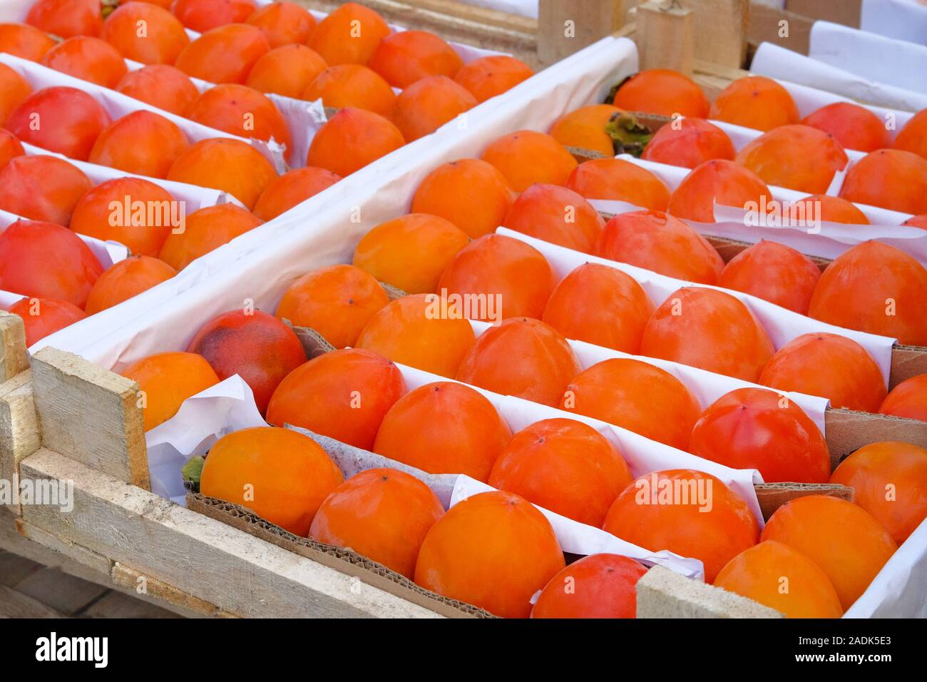 Organische, orange Kaki im Holzkasten sind an den lokalen Obst Landwirtschaft Markt verkauft. Verkauf der Früchte nach der Ernte. Persimonen in greengrocery. Stockfoto