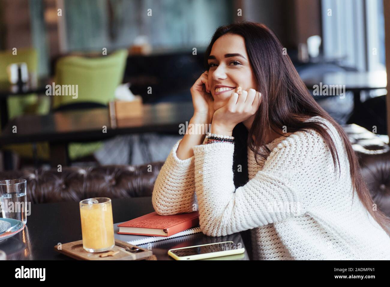 Schöne Frau. Fröhliche blonde Mädchen sitzen im Restaurant mit gelben Getränk auf den Tisch und lächelt Stockfoto