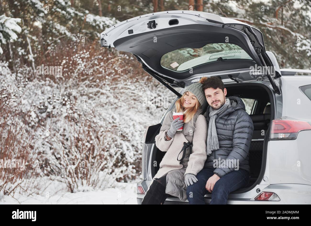 Fühlt sich Zufriedenheit durch umarmen einander. Nettes Paar haben Wochenende an der Landschaft im Winter. Das Sitzen auf dem hinteren Teil des modernen Auto Stockfoto