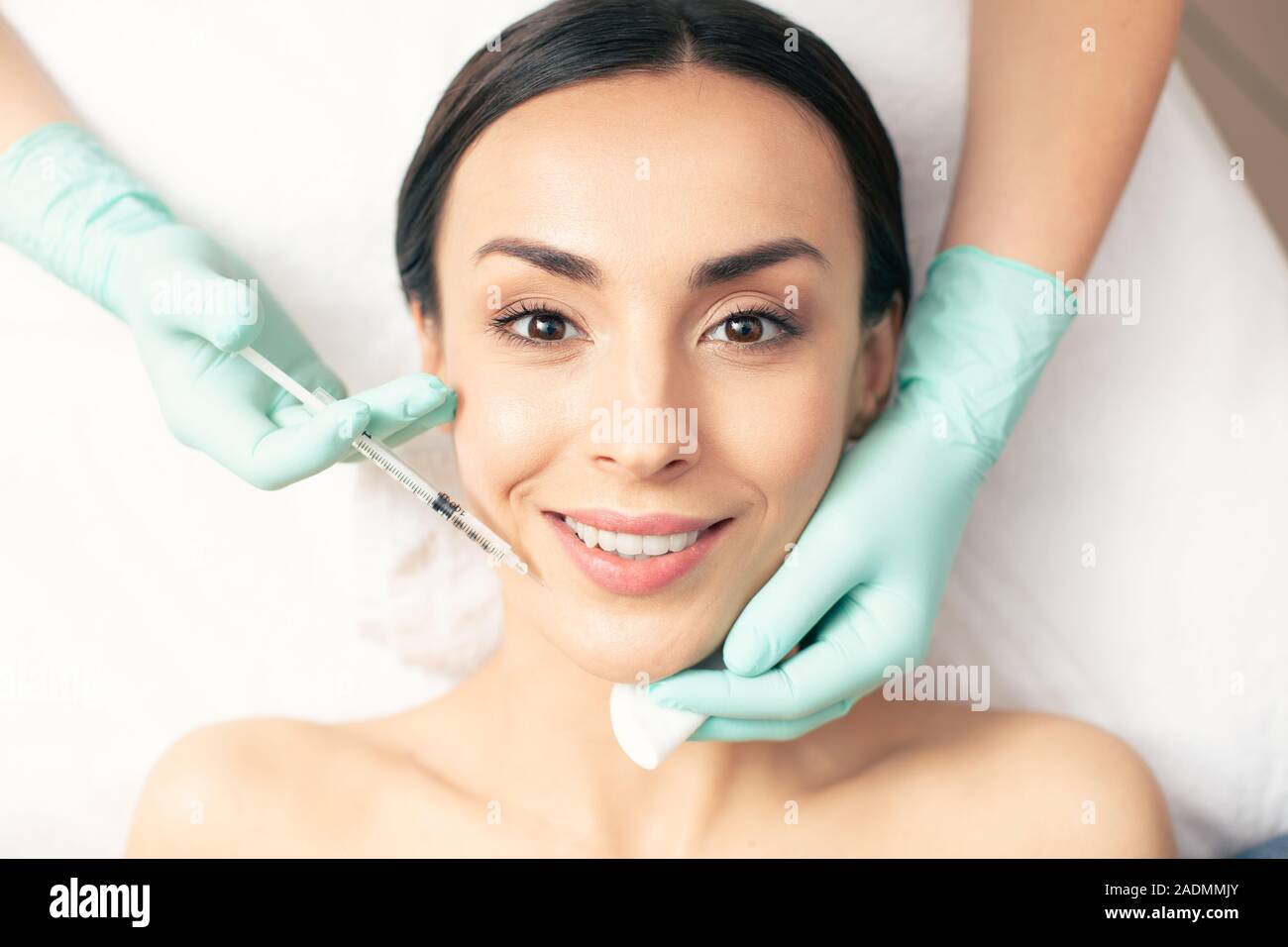Junge Dame suchen froh, die während der Injektion im Beauty Salon Stockfoto