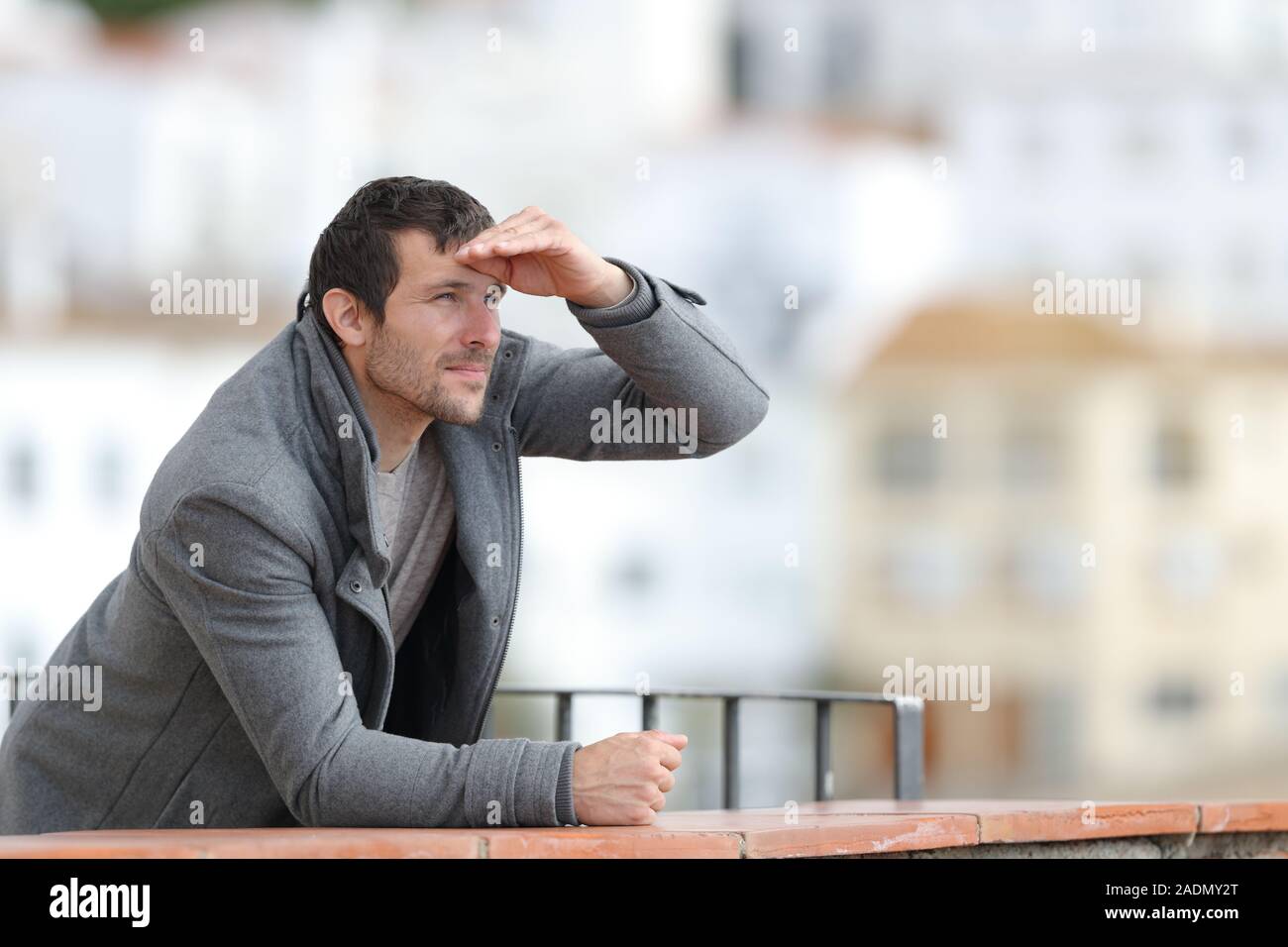 Mann mit der Hand auf der Stirn stehen in einem Balkon draußen in einer ländlichen Stadt Stockfoto