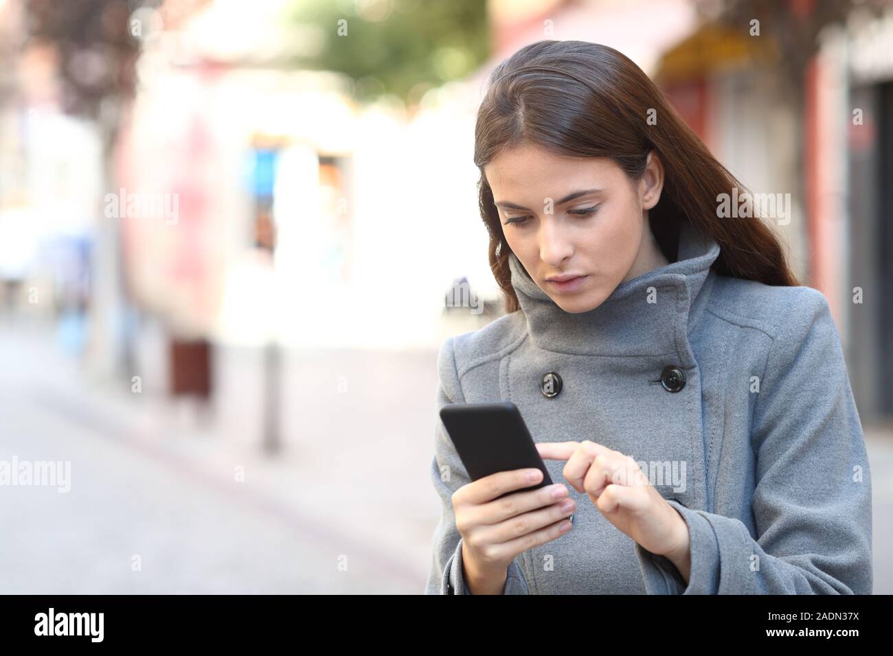 Schwere Mädchen im Winter Prüfung Handy zu Fuß auf der Straße Stockfoto