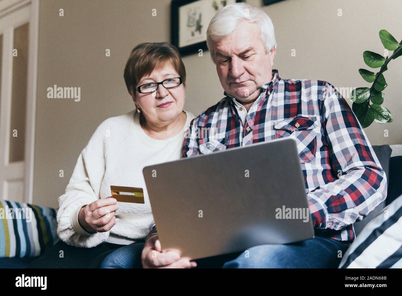 Ältere Menschen kaukasischen Paar tun Einkäufe online auf der Couch zu Hause, Laptop- und lächelnd Stockfoto Ältere Menschen kaukasischen Paar tun Einkäufe online auf der Couch zu Hause, Laptop- und lächelnd Stockfoto