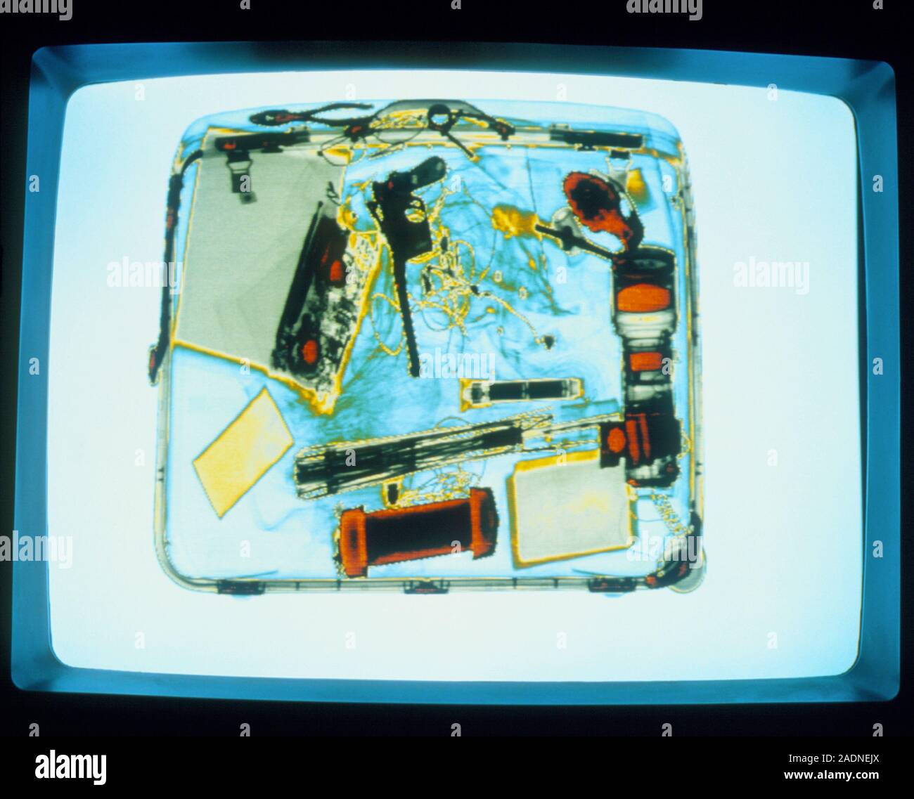 Farbige Bild, das von einem Flughafen X-ray Scanner. Farbcodierung zeigt  ein Buch (graues Objekt, oben links), einen Block von Paraffin (Hellgrau,  unten Rig Stockfotografie - Alamy