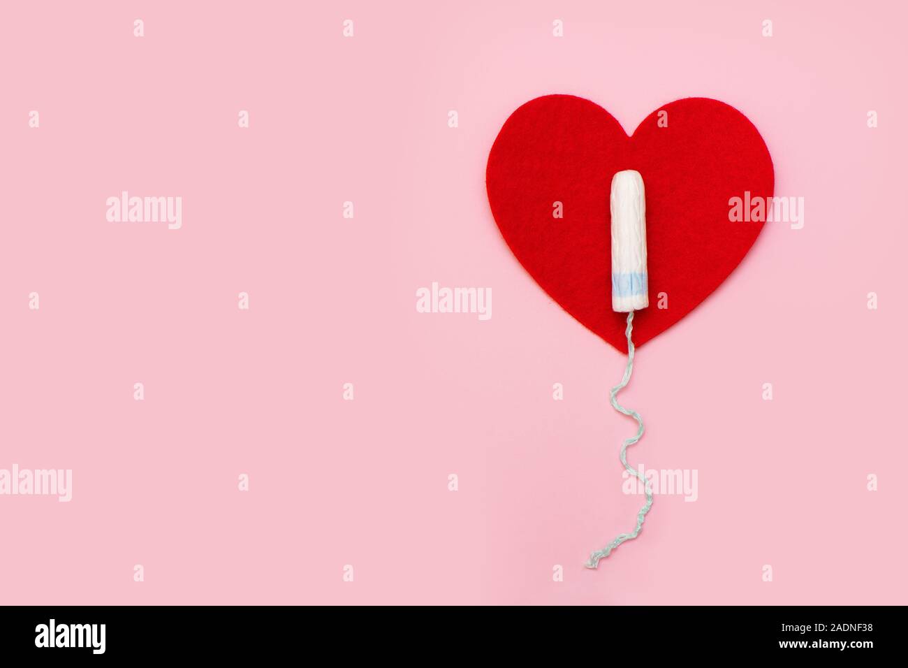 Eine weiße Tampon liegt auf einem roten Fleece Herz auf rosa Hintergrund. Stockfoto