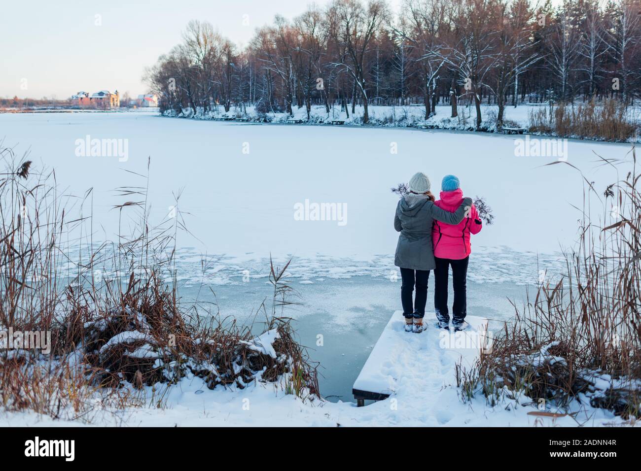 Winter gehen. Mutter und erwachsene Tochter bewundern verschneiten See Landschaft. Familie umarmen, erholsamer Urlaub Stockfoto