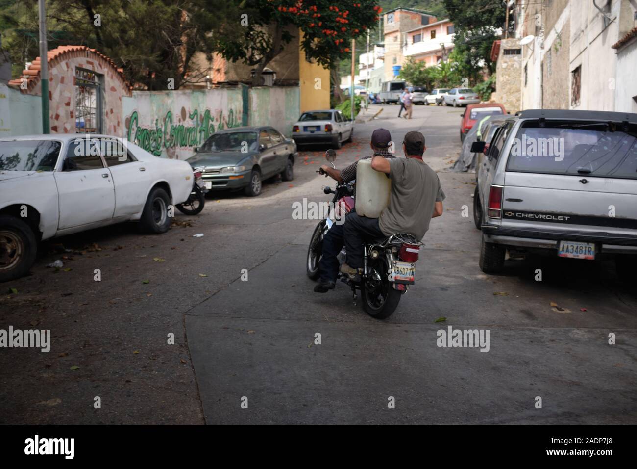 Caracas, Miranda, Venezuela. 29 Nov, 2019. Den Ehemann von Aura und Sohn fahren mit vollen Behältern nach Hause zu bringen, während die Aura hält die andere. Aura Graciela Sarmiento, Alter 56, und ihr Mann Jose Alberto Abreu, Alter 62, habe keine fliessendes Wasser in Ihrem Haus in 4 Jahren. Aura arbeitet in ein Geschäft mit Büromöbeln und Jose ist ein Mechaniker. Sie leben in der Nähe von Altos de Lidice in Caracas Venezuela. Altos de Lidice ist ein historisches Chavista Nachbarschaft. Aber Aura ist pro-Opposition, und hat nie die Chavez Regime unterstützt, obwohl sie in diesem pro lebten - chavín Stockfoto