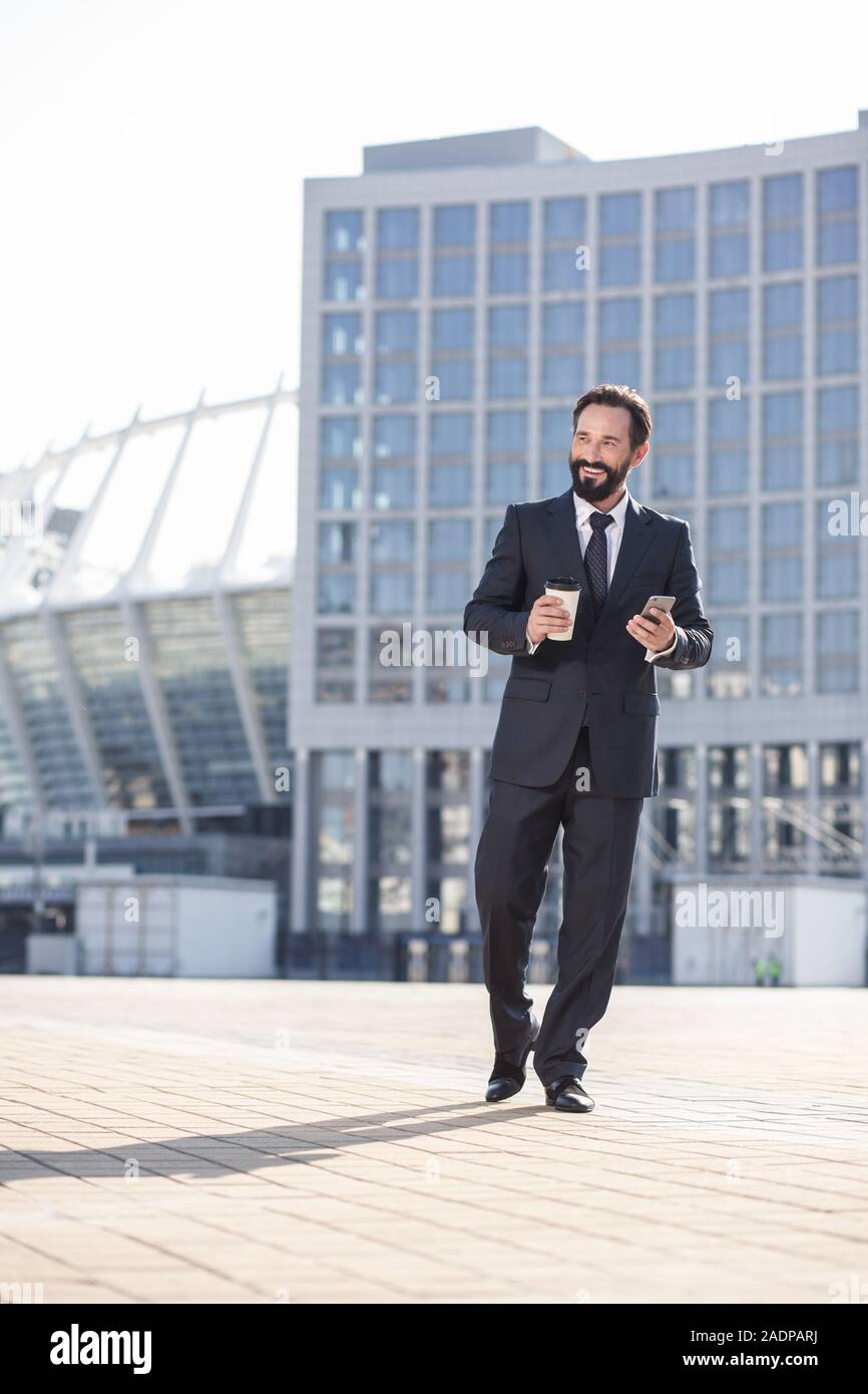 Volle Länge eines fröhlichen bärtigen Geschäftsmann zu Fuß in der Stadt Stockfoto