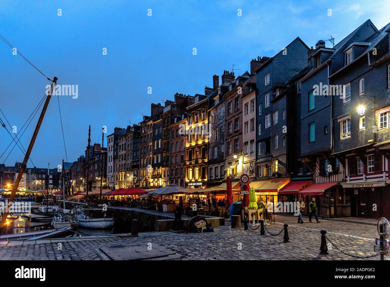 Boote angedockt im alten Hafen von Honfleur, Frankreich mit seinen strassencafés an der blauen Stunde Stockfoto