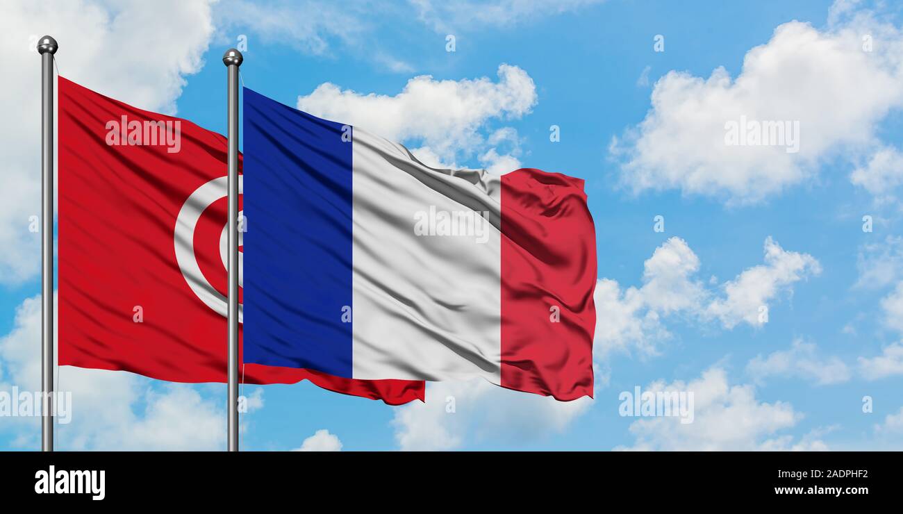 Tunesien und Frankreich Flagge im Wind gegen Weiße bewölkt blauer Himmel zusammen. Diplomatie Konzept, internationale Beziehungen. Stockfoto