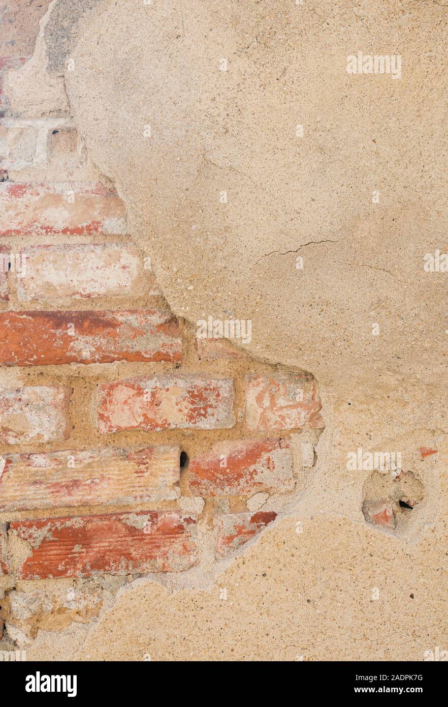 Nahaufnahme eines alten, beschädigten & verputzt beige Wand. Gips ist teilweise abgeblättert enthüllt alten Ziegelsteinen. Hochauflösende full frame strukturierten Hintergrund. Stockfoto