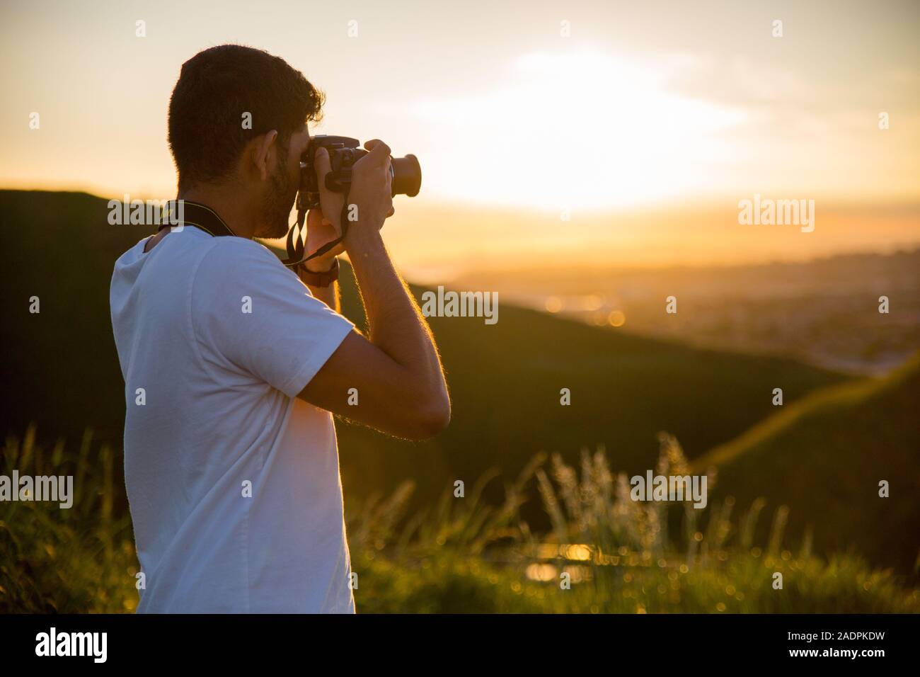 Ein Mann nimmt ein Foto mit seiner Nikon Kamera bei einem Sonnenuntergang am Gipfel des Mount Wellington in Auckland, Neuseeland. Stockfoto