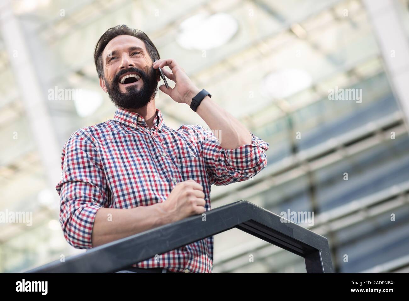 Low Angle einen angenehmen lächelnden Mann in einem Telefongespräch Stockfoto