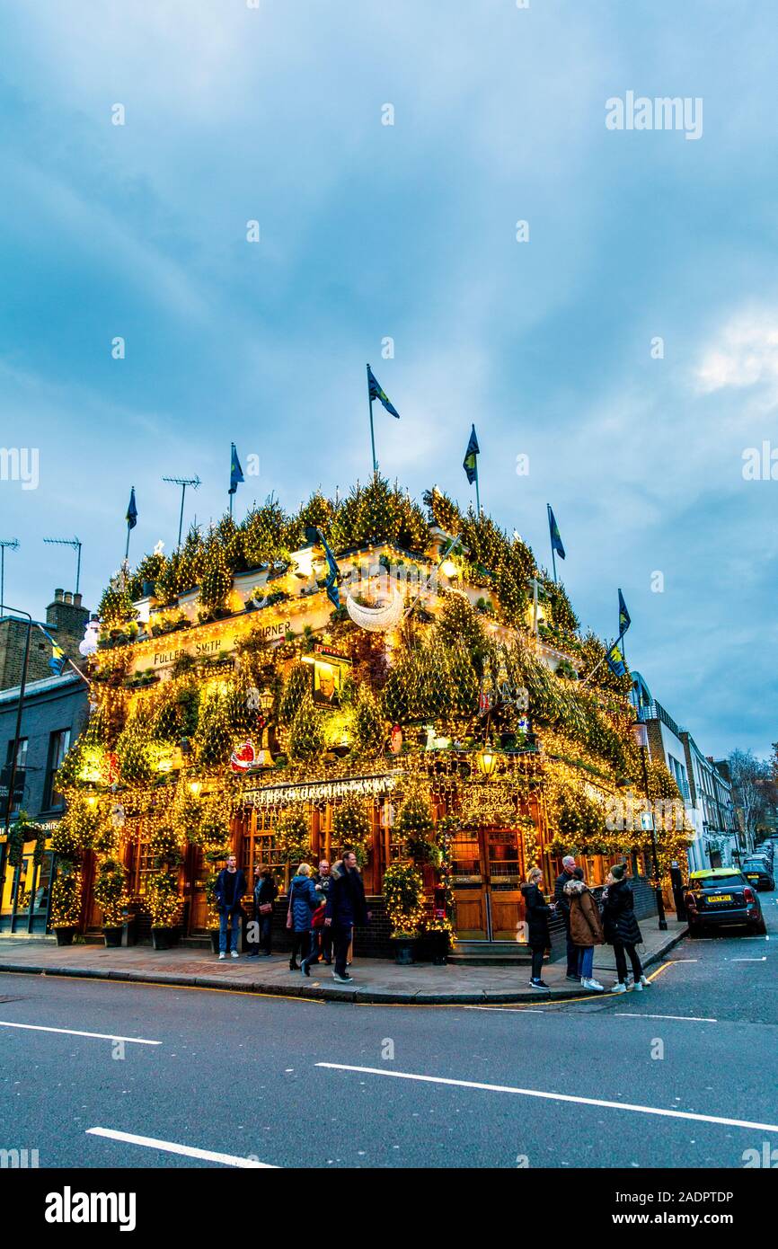 Opulente Weihnachtslichter und Dekorationen an der Fassade des Churchill Arms Pub, London, Großbritannien Stockfoto