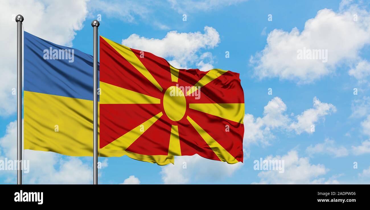 Die Ukraine und Mazedonien Flagge im Wind gegen Weiße bewölkt blauer Himmel zusammen. Diplomatie Konzept, internationale Beziehungen. Stockfoto