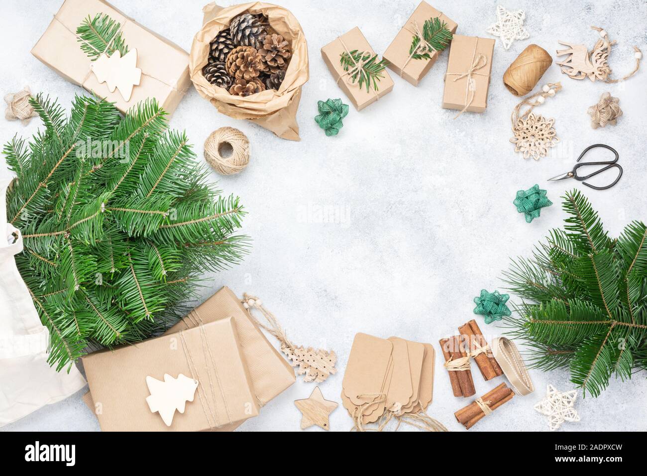 Null Abfall umweltfreundliche Weihnachten Rahmen. Xmas Tree Branches in Baumwolle, wiederverwendbare Tasche, präsentiert in braunes Papier, kiefernzapfen Tags hessische Cinnamon Sticks für die Dekoration. Ansicht von oben, selektiver Fokus Stockfoto