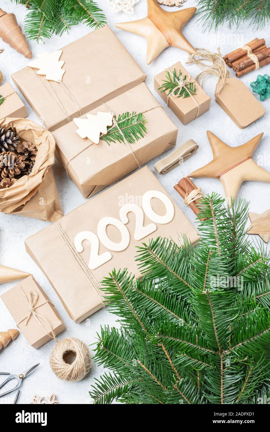 Null Abfall umweltfreundlich, Weihnachten, Neues Jahr 2020 Hintergrund. Xmas Tree Branches präsentiert in braunes Papier, kiefernzapfen Tags hessische Cinnamon Sticks für die Dekoration. Ansicht von oben, selektiver Fokus Stockfoto