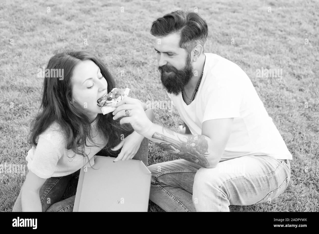 Pizza. Sommer Picknick auf dem grünen Rasen. Familie Wochenende. verliebtes Paar dating. Fast food. bärtiger Mann Hipster und adorable Girl essen Pizza. glückliches Paar essen Pizza. Seine Freundin füttern. Stockfoto