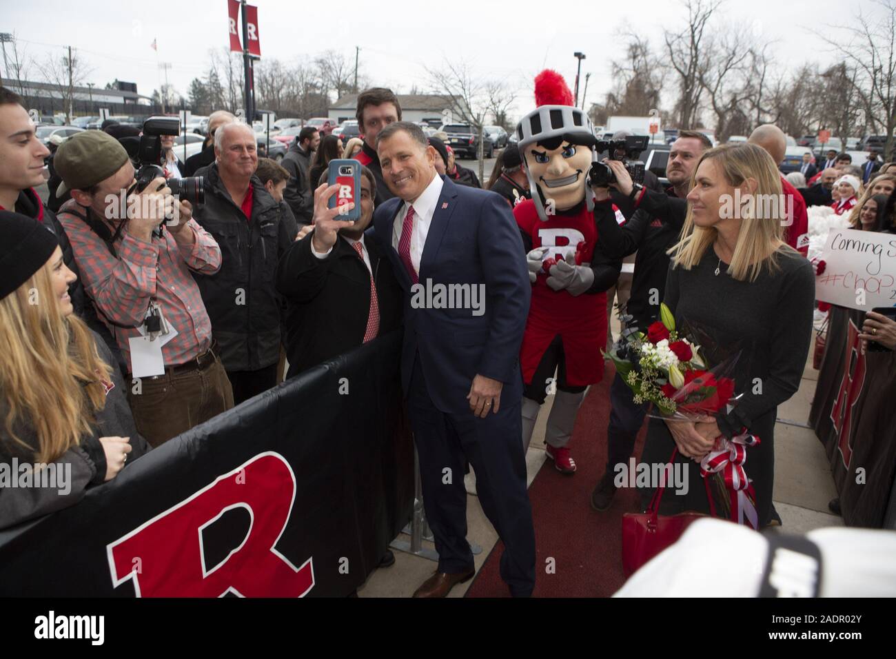 Piscataway, New Jersey, USA. 4. Dez, 2019. Rutgers Head Coach Greg Schiano, mit einem Rutgers Ventilator, während von anderen Rutgers Fans vor dem Betreten des Hale Centre auf seine Rückkehr an die Universität als Fußball-Trainer nach dem Coaching in der NFL und andere College Teams empfangen wird. Credit: Brian Zweig Preis/ZUMA Draht/Alamy leben Nachrichten Stockfoto