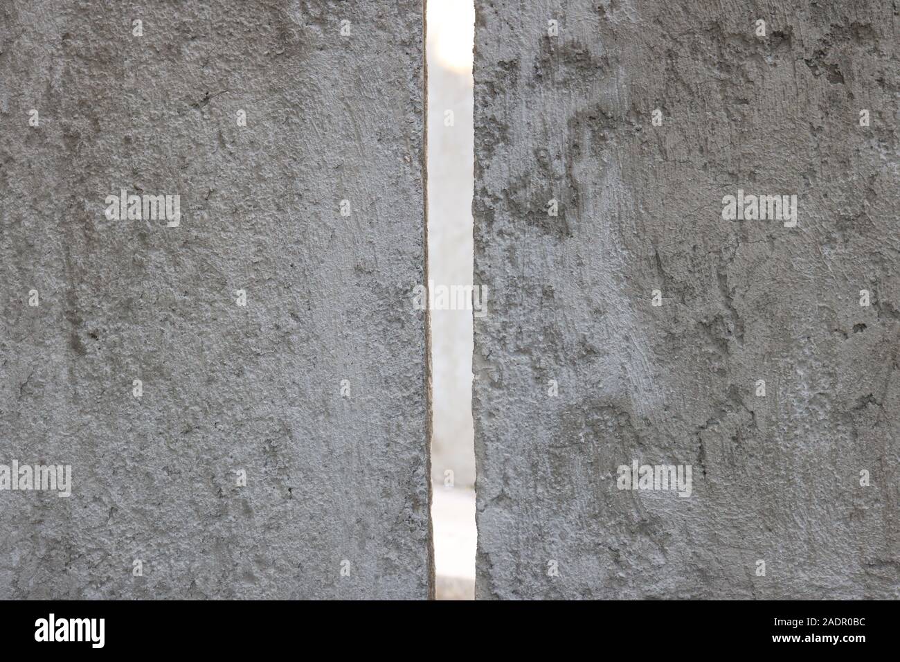 Zementwand mit einer Spitze durch Schlitz, die das Licht durchlässt Stockfoto